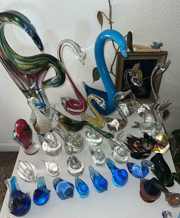 Collection of colorful glass bird figurines arranged on a white surface in a home display.