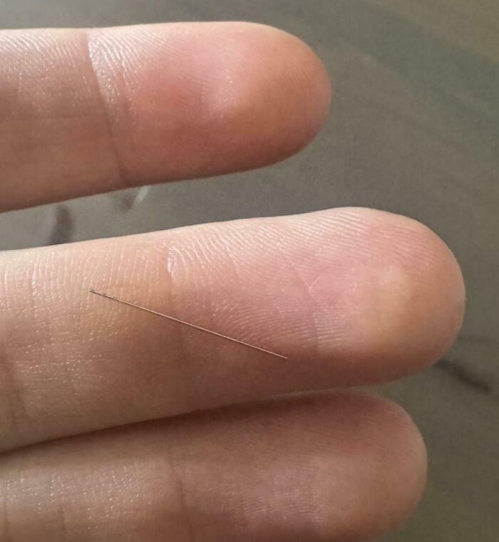 Close-up of a thin, tiny metal wire on human fingers, showcasing one of the fascinating pictures for curious minds.