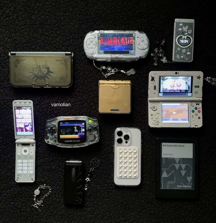 Collection of unusual handheld gaming consoles and devices displayed on a black surface in a home collection.