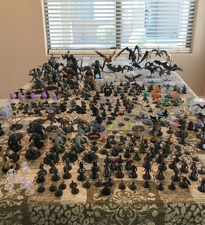 Extensive and unusual collection of fantasy miniature figures displayed on a table in a home setting.