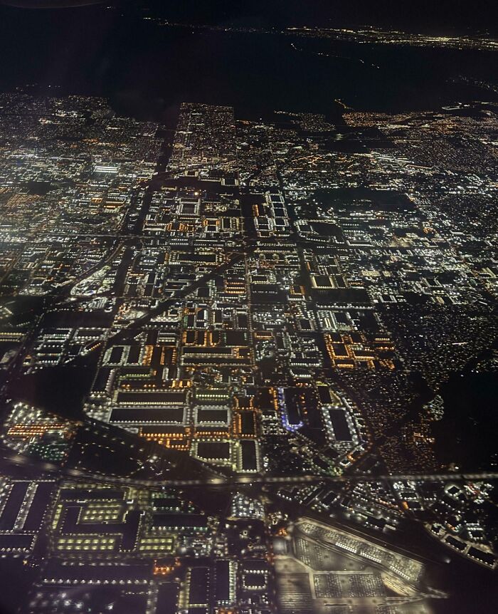 Aerial night view of a sprawling cityscape illuminated by thousands of lights for curious minds to explore.