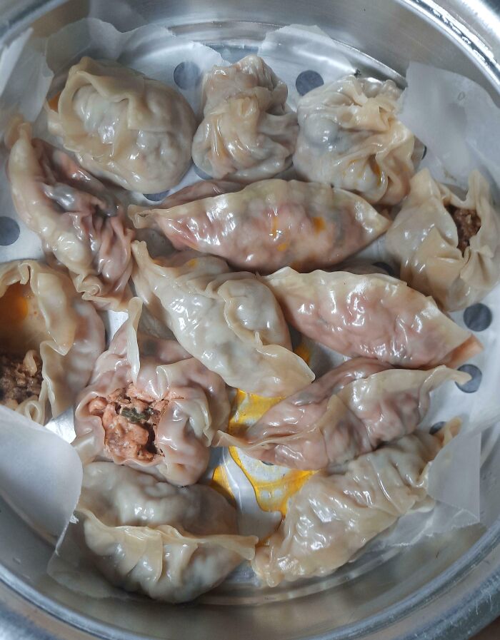 Steamed dumplings with uneven shapes and filling spills, showcasing a cooking fail and accident in the kitchen.