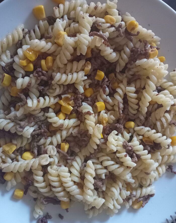 Plate of pasta with corn and cooked ground beef showing a cooking fail with unevenly mixed ingredients and texture.