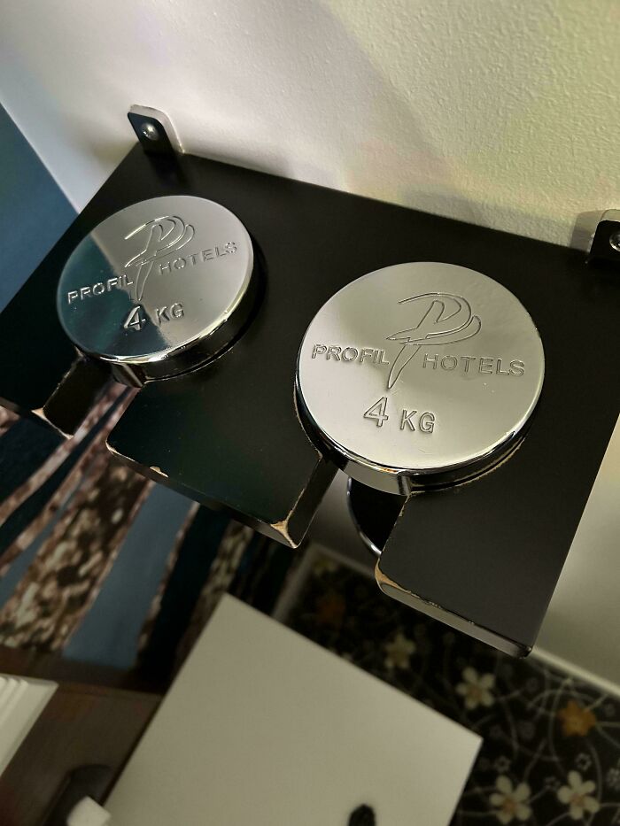 Chrome 4 kg weights with Profil Hotels branding on a sleek black hotel gym design rack detail.
