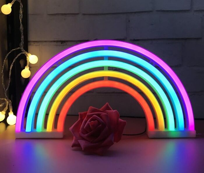 Neon rainbow mood lamp glowing on a table with a red rose and fairy lights creating an instant mood lift.