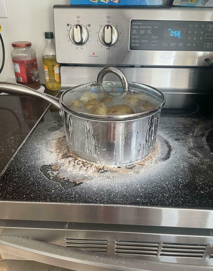 Stove with a pot boiling over causing a cooking fail and mess on the cooktop in a kitchen setting.