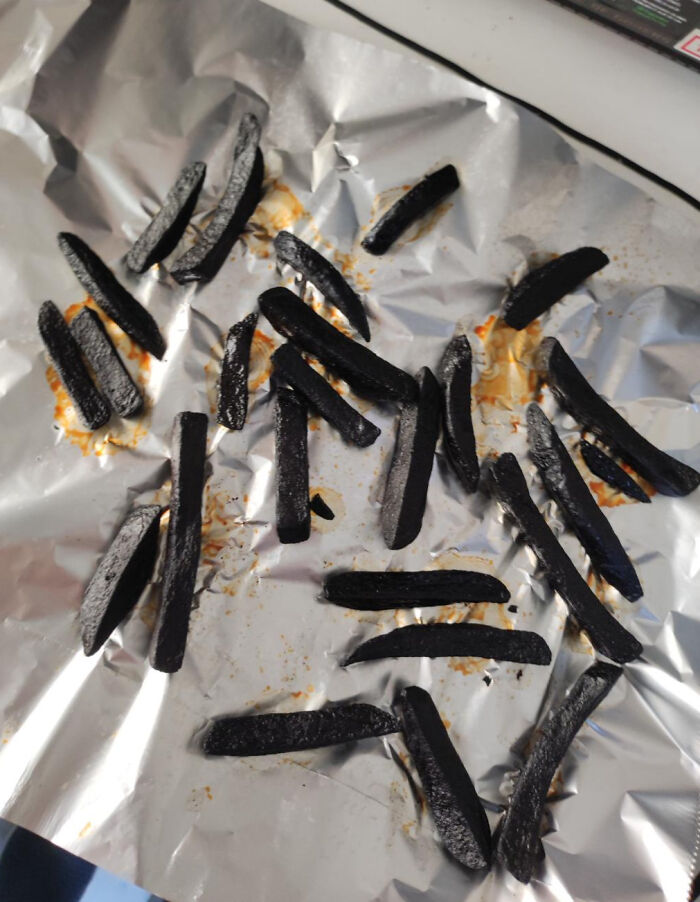 Burnt fries scattered on a foil-lined tray, showcasing a funny and painful cooking fail accident in the kitchen.