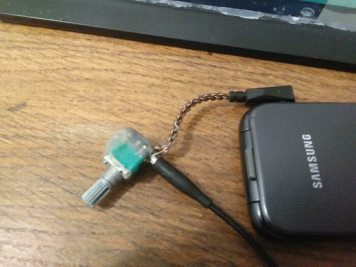 DIY project showing a homemade audio volume control k**b attached to a Samsung device on a wooden surface.