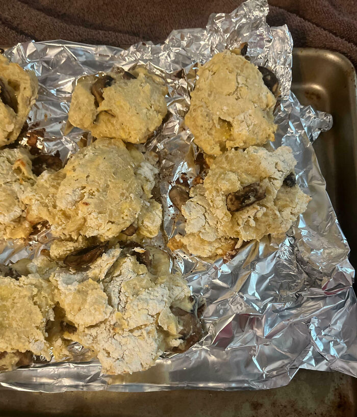 Poorly baked mushroom biscuits on a foil-lined tray showing cooking fails and kitchen accidents.