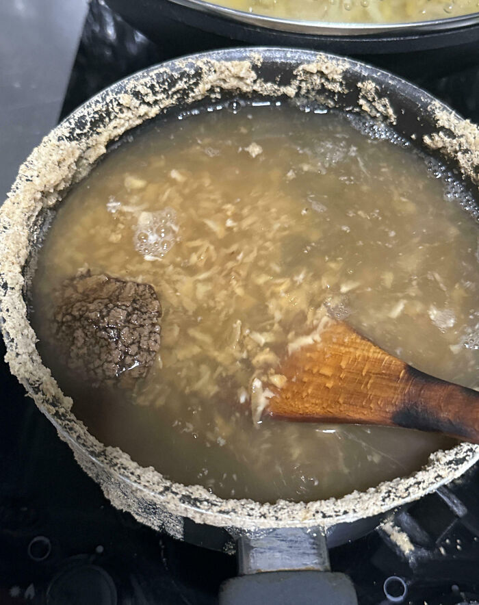 Pot with overboiled rice and burnt residue on the edges, showing a classic cooking fail accident with wooden spoon inside.