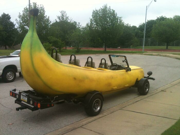 Custom DIY banana-shaped car parked on street, showcasing a creative and unusual DIY project design.