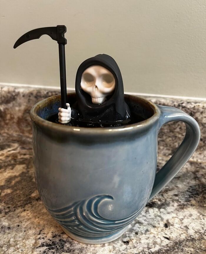 Small grim reaper figurine floating in a blue mug filled with liquid, one of the ridiculous purchases that just kind of make sense.