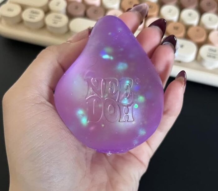 Hand holding a purple glittery Neo Doh stress ball, one of the ridiculous purchases that just kind of make sense.
