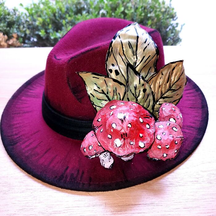 Red hat decorated with handmade DIY mushroom and leaf craft embellishments, showcasing creative DIY projects.