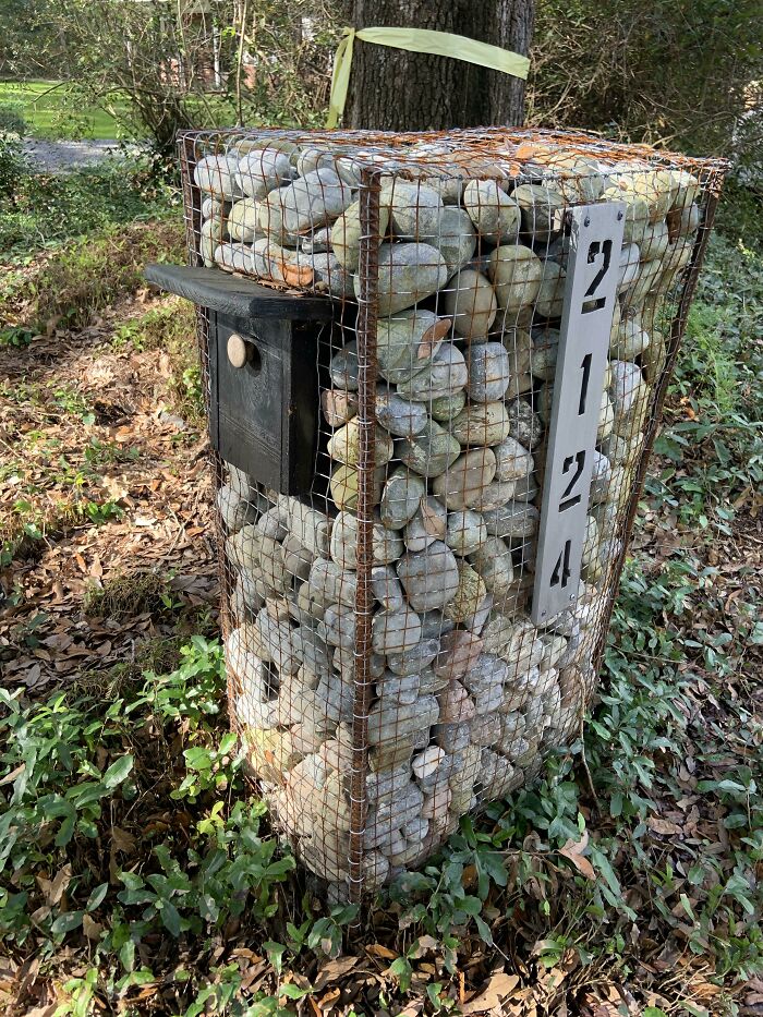 DIY project of a mailbox enclosure made from wire mesh filled with large rocks, blending creativity with functionality outdoors.