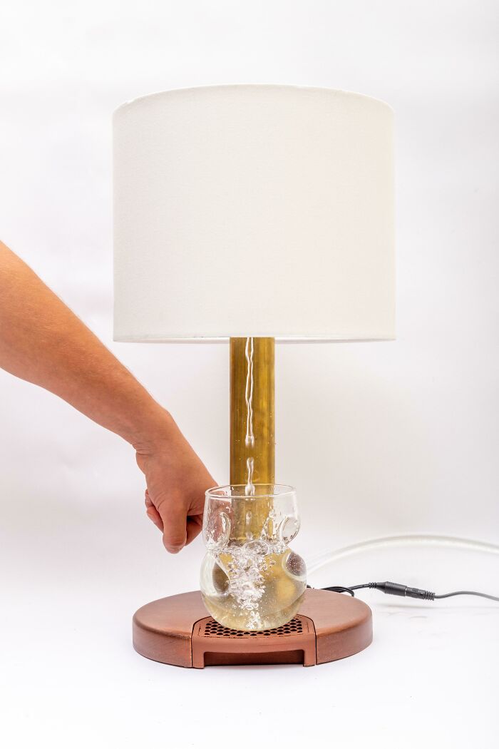 Hand turning on a unique DIY lamp with a glass and water feature, showcasing creative and unusual DIY projects.