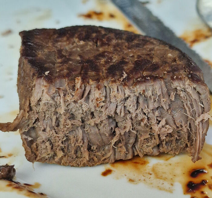 Overcooked and dry piece of meat on a plate, showcasing a cooking fail in a kitchen setting.