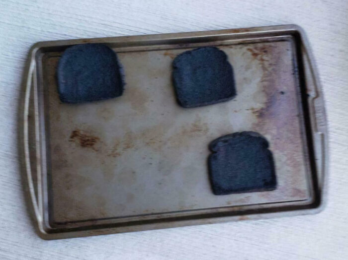 Three slices of burnt toast on a baking tray showing a cooking fail and accident in the kitchen.
