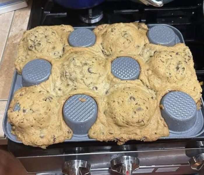 Overfilled muffin pan with cookie dough spilling over, showcasing a cooking fail and kitchen accident.