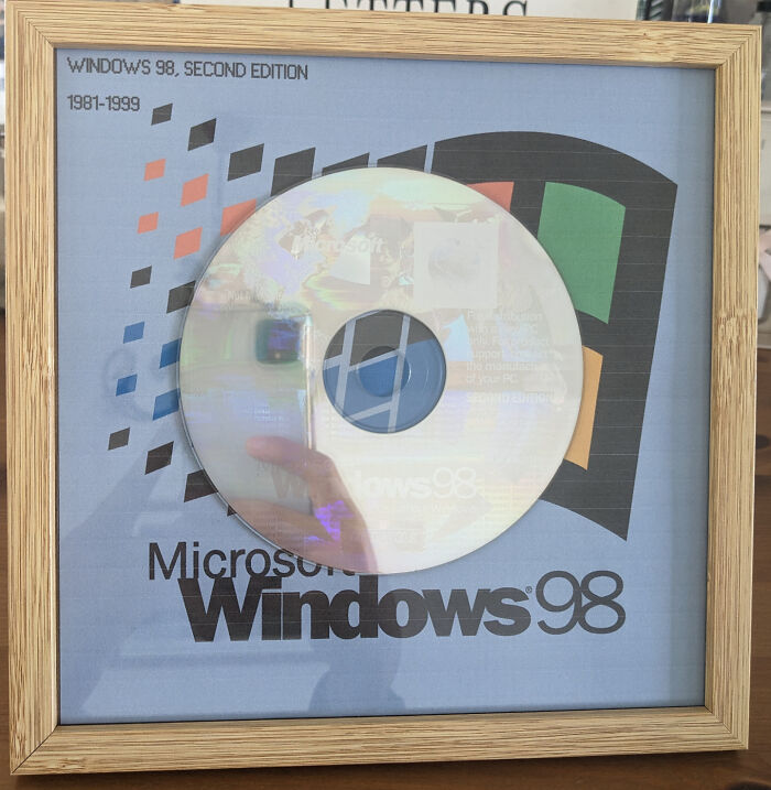 Framed Windows 98 CD art with vintage logo, showcasing a creative DIY project that blends tech nostalgia and design.