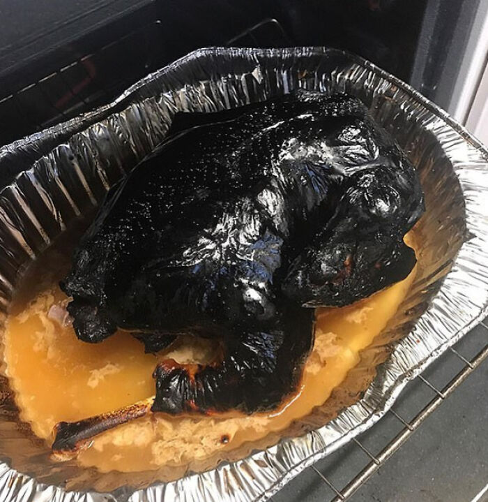 Severely burnt whole chicken in an aluminum pan showing a painful cooking fail and accident in the kitchen.