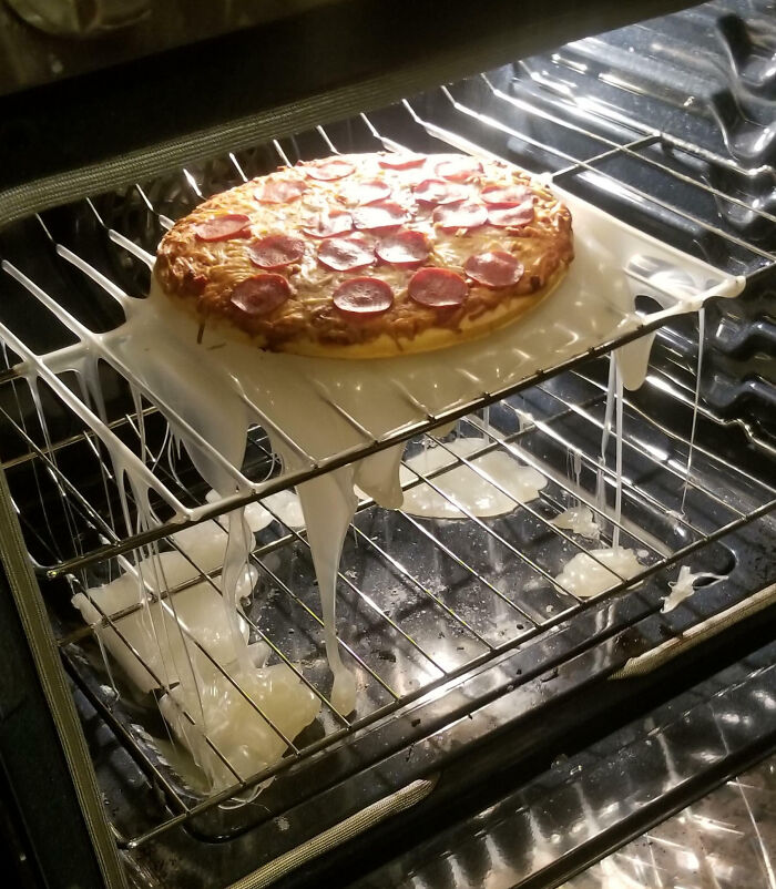 Pepperoni pizza baking in an oven with melted plastic sheet causing a cooking fail and accident.
