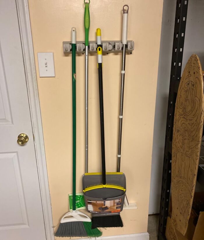 Cleaning tools hanging on a wall rack, one with dustpan, showcasing popular Amazon finds for home organization.