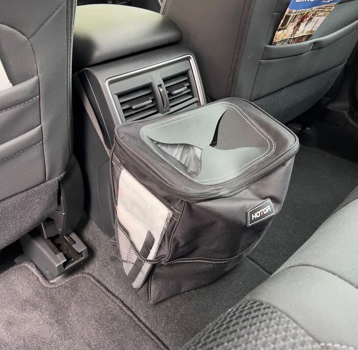 Compact black car trash bag placed on the backseat floor, one of the popular Amazon finds on many wishlists right now.