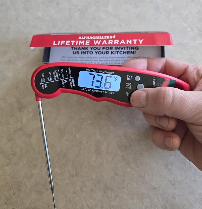 Hand holding a digital cooking thermometer displaying 73.6°F, one of the top Amazon finds on wishlists.