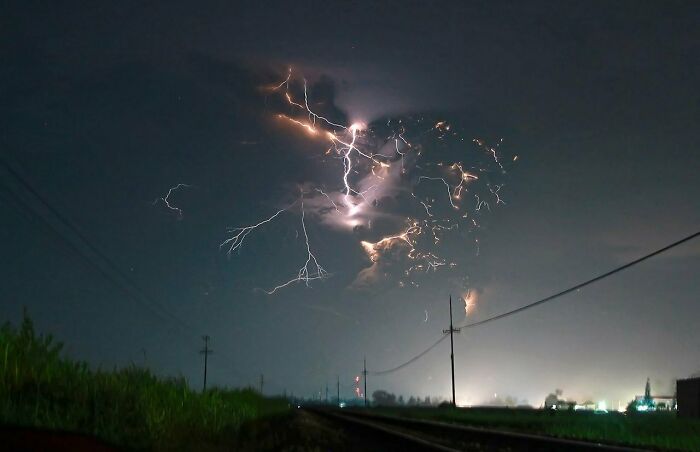 Unusual lightning display at night over power lines and fields, an interesting thing requiring a double take to realize what it is.