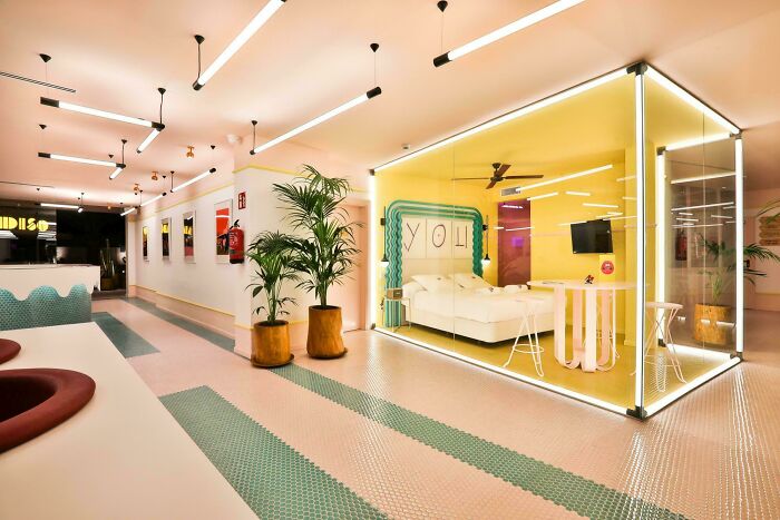 Modern hotel interior featuring creative glass-walled room design and vibrant lighting, showcasing genius hotel design decisions.