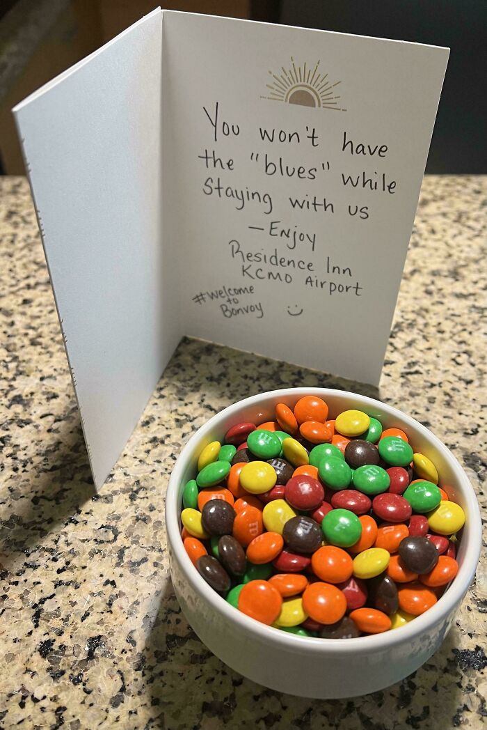 Bowl of colorful candies with a handwritten welcome card, showcasing genius hotel design decisions for guest experience.