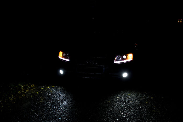 Car headlights glowing in darkness on a wet road, an interesting scene requiring a double take to realize what it is.