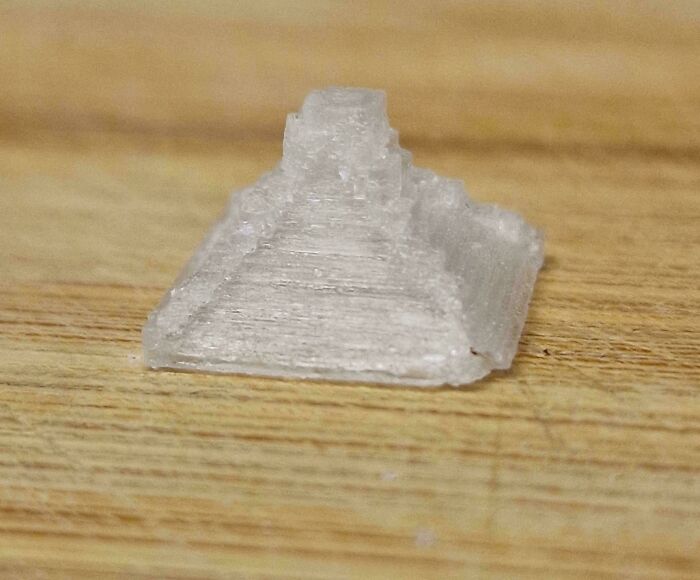 Miniature clear pyramid on wooden surface, an interesting thing requiring a double take to realize its true scale.