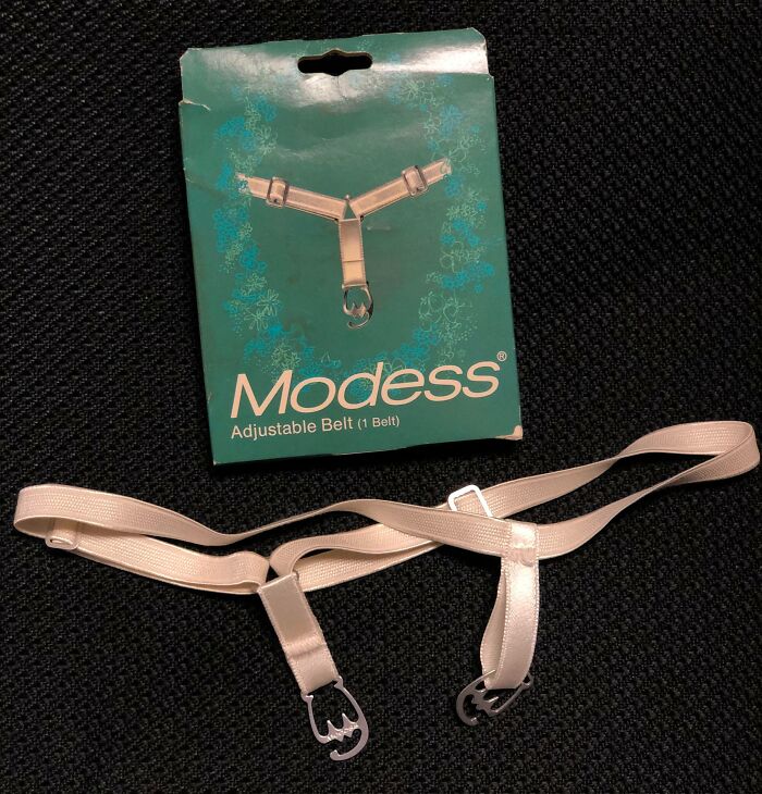 Vintage Modess adjustable belt with metal clasps displayed on black fabric, portraying how things used to look in fashion accessories.