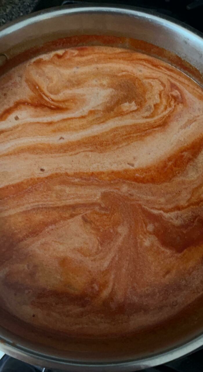 Swirling pattern in a pot of liquid that looks like a painting, an interesting thing requiring a double take to realize.