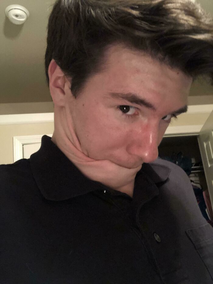 Young man with distorted facial expression showing bizarre flexibility of the human body in an indoor setting.