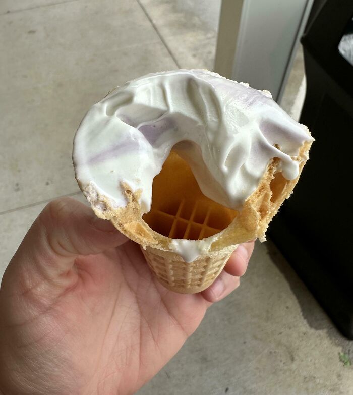Hand holding an ice cream cone with a melted and broken top, a mildly infuriated moment captured in a new pic.
