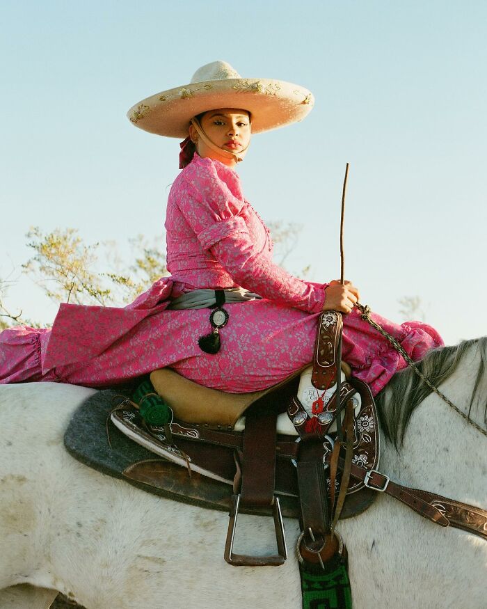 Female rodeo rider in traditional attire atop a white horse showcasing the power and beauty of all-female rodeo riders.