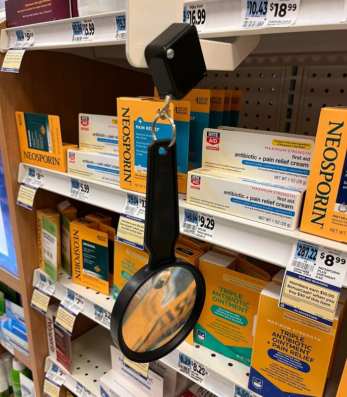 Magnifying glass hung on a pharmacy shelf as a clever solution to help read small print on medication packaging.