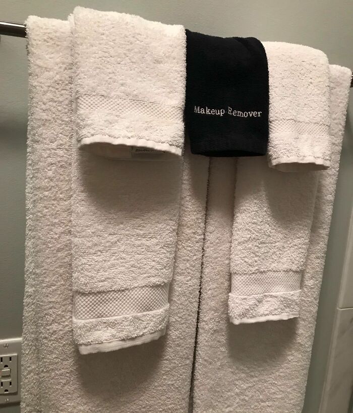 White towels hung with a labeled black makeup remover cloth showing clever solutions for overlooked household issues