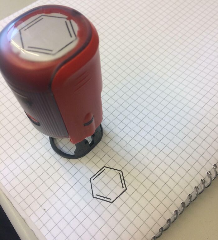 Red and black stamp creating a precise hexagon design on graph paper, showcasing clever ways people solved issues.