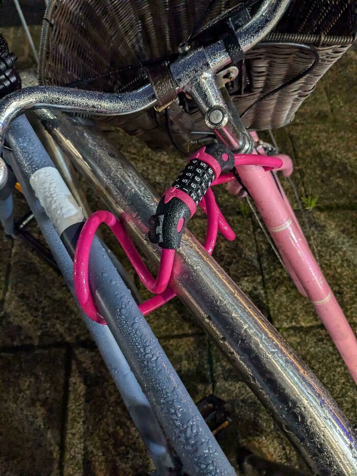 Bicycle locked awkwardly with a pink combination lock on a metal railing, illustrating mildly infuriated moments.