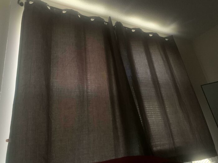 Dark curtains partially open with light seeping through, illustrating a scene from mildly infuriated people who shared ruined mood moments.