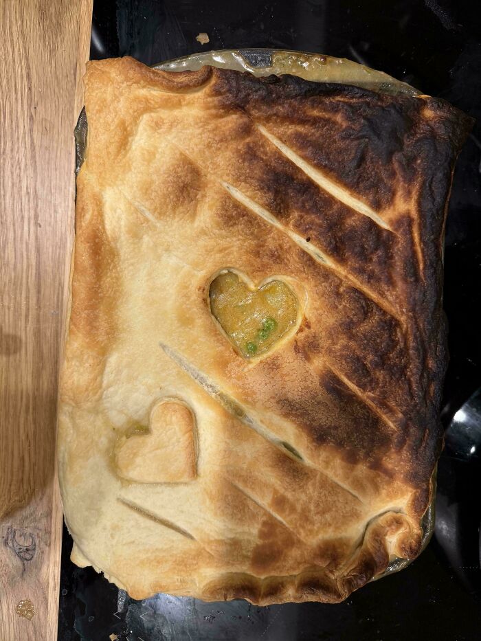 Partially burnt pie crust with two heart-shaped cutouts revealing filling, illustrating mildly infuriated mood ruined by cooking fail.