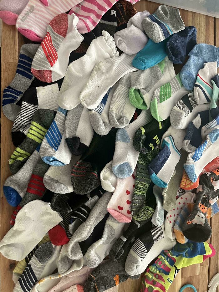 Pile of unmatched socks scattered on wooden floor, illustrating a common mildly infuriated mood-ruining situation.