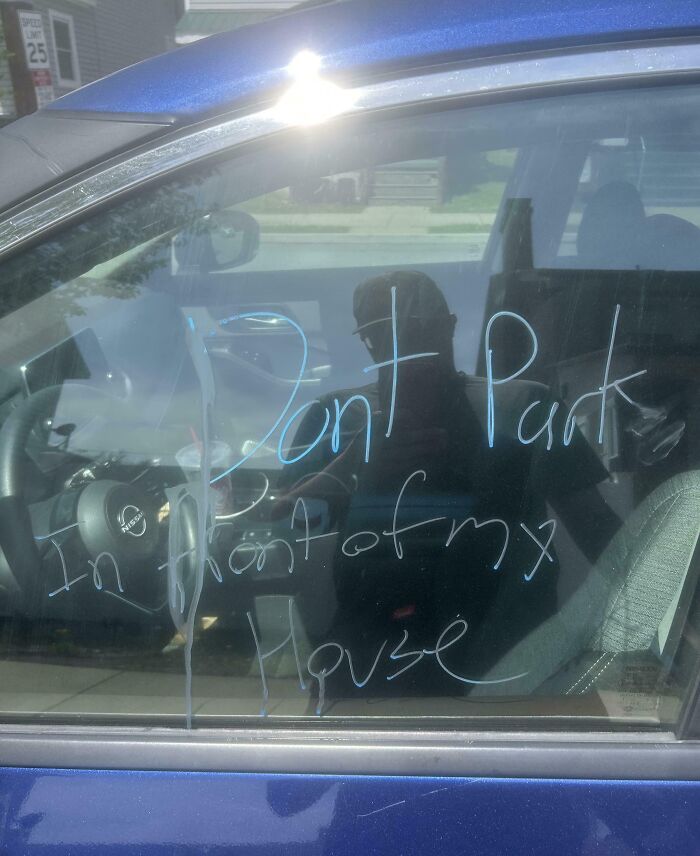 Blue car window with a handwritten message saying dont park in front of my house, illustrating mood-ruining moments shared by infuriated people.