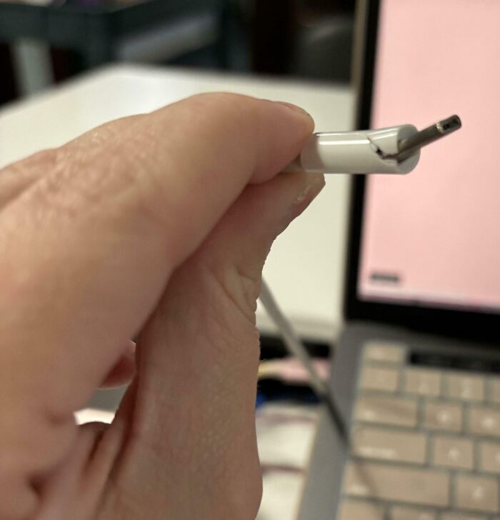 Close-up of a hand holding a c*****d charging cable causing mildly infuriated mood frustration.