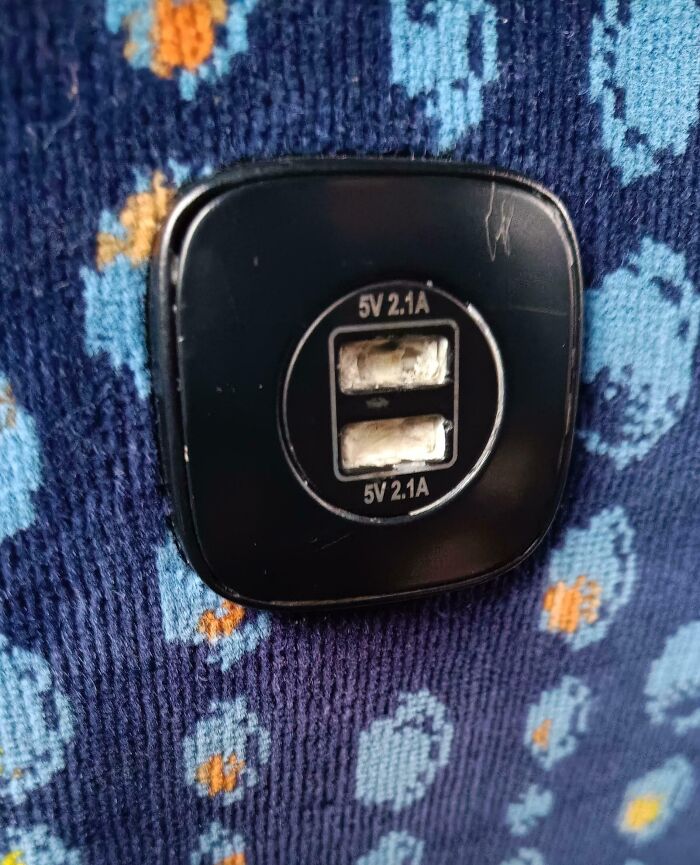 Damaged USB charger ports labeled 5V 2.1A on a floral patterned fabric, causing mild infuriation and mood ruin.