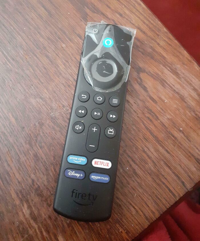 Fire TV remote with worn-out sticky tape on directional pad, illustrating a mildly infuriated mood ruined by damage.